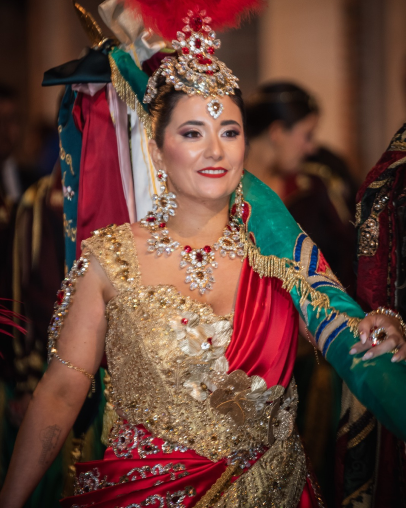 Mujer con traje festero dorado, corona y adornos artesanales en las fiestas de Moros y Cristianos